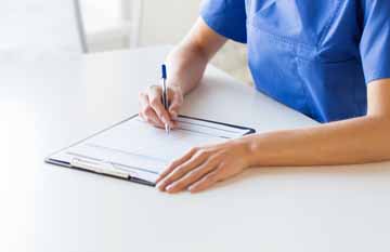 close up of doctor or nurse writing to clipboard